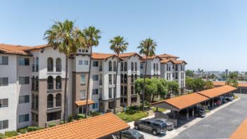 A row of apartment buildings with a parking lot in front.